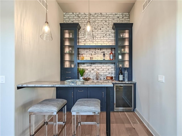 bar with visible vents, baseboards, wine cooler, wet bar, and wood finished floors