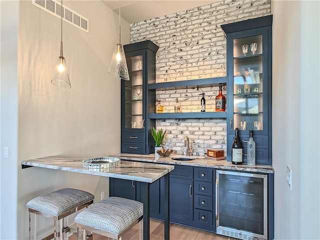 bar featuring beverage cooler, visible vents, brick wall, indoor wet bar, and hanging light fixtures