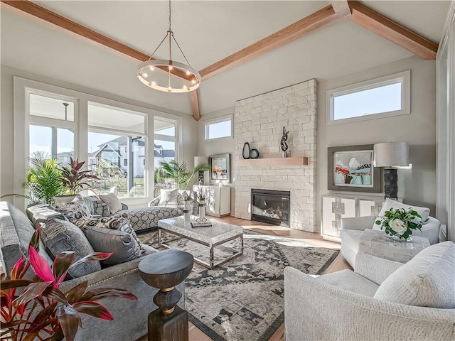 living room with a chandelier, beamed ceiling, a healthy amount of sunlight, and a fireplace