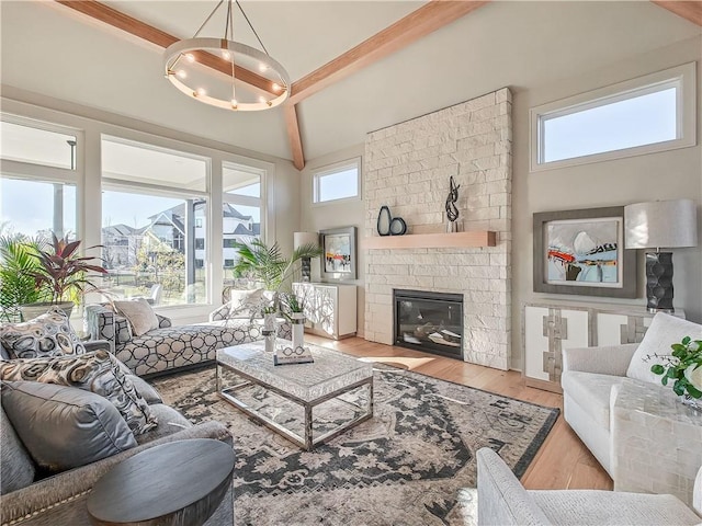 living room with beam ceiling, a notable chandelier, plenty of natural light, and wood finished floors