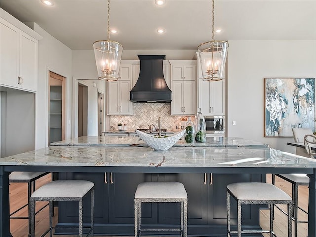 kitchen featuring a chandelier, a spacious island, white cabinetry, and custom range hood