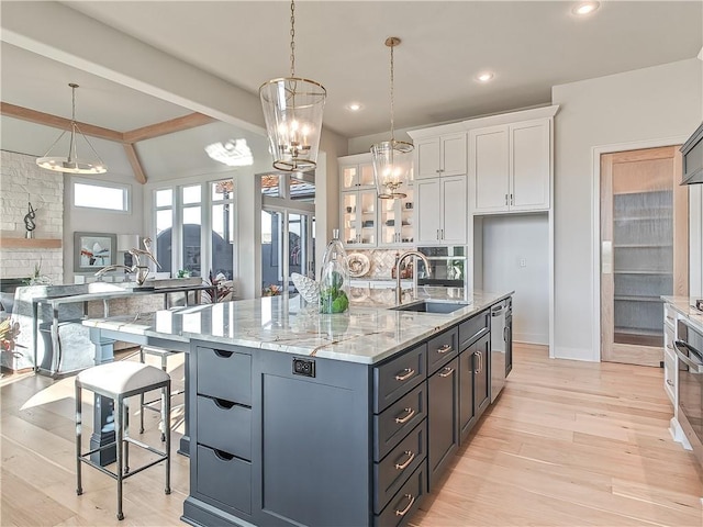 kitchen with light stone counters, a sink, glass insert cabinets, white cabinetry, and backsplash