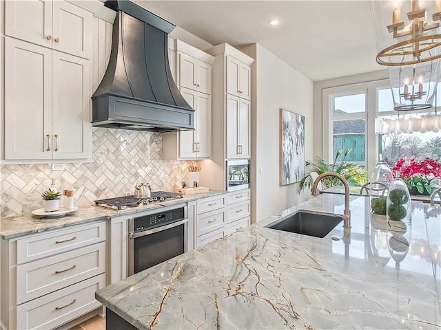 kitchen with custom range hood, a sink, tasteful backsplash, stainless steel appliances, and light stone countertops