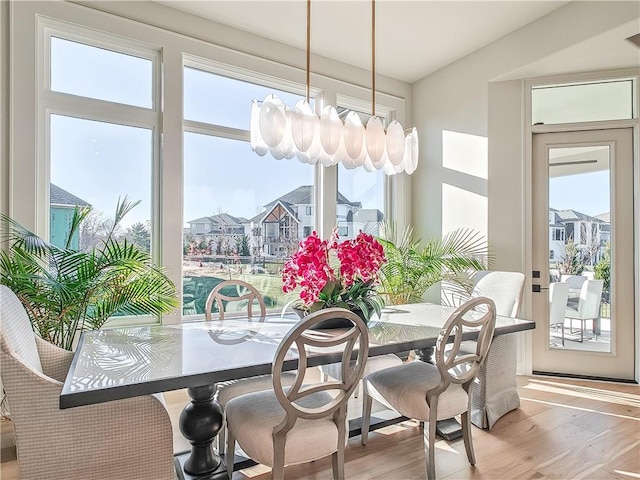 dining area with lofted ceiling, wood finished floors, a residential view, and a chandelier