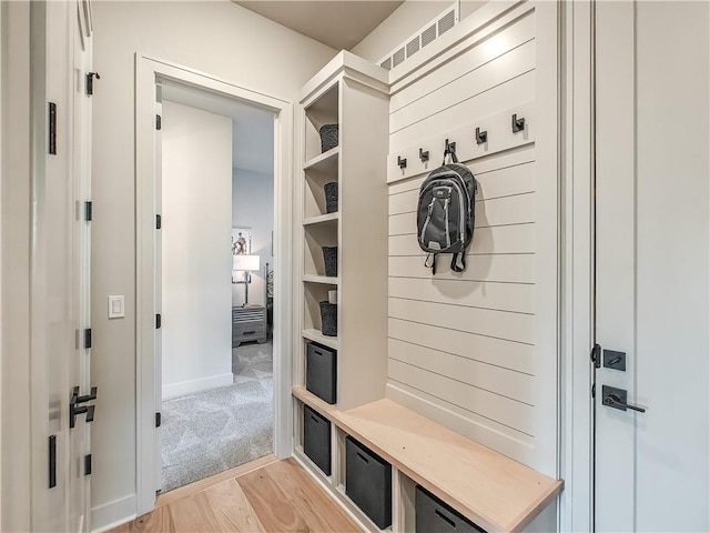 mudroom featuring visible vents, light colored carpet, and light wood-style floors