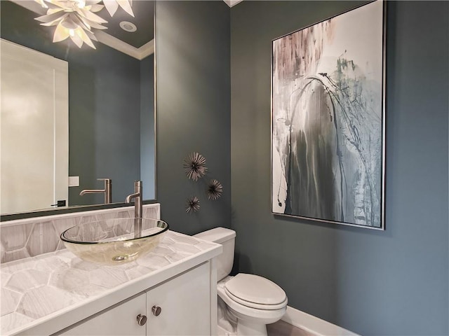 half bathroom with crown molding, baseboards, ceiling fan, toilet, and vanity