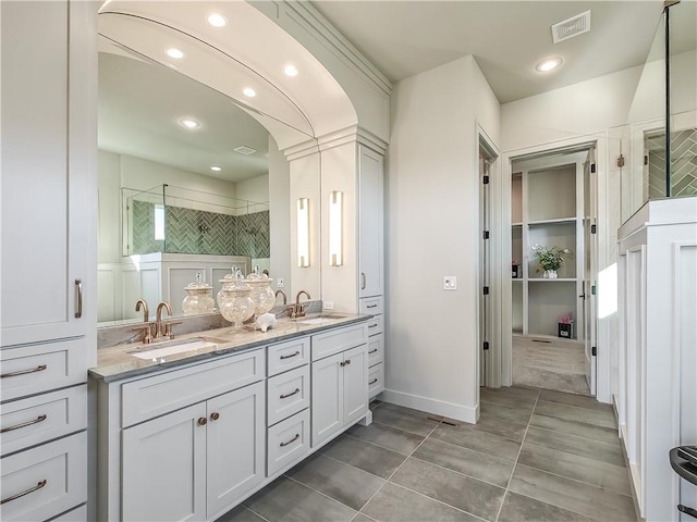 bathroom featuring tile patterned flooring, a shower stall, double vanity, and a sink