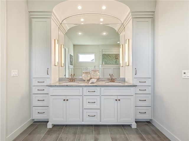 bathroom featuring double vanity, baseboards, and a sink