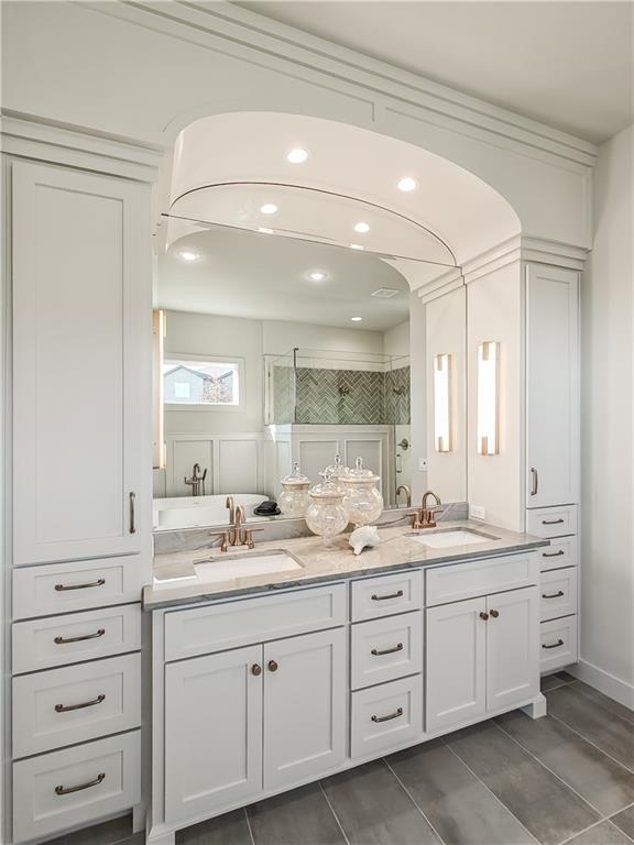 full bathroom featuring double vanity, tiled shower, and a sink