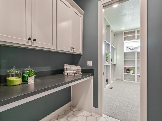 interior space with light carpet, a textured ceiling, and baseboards