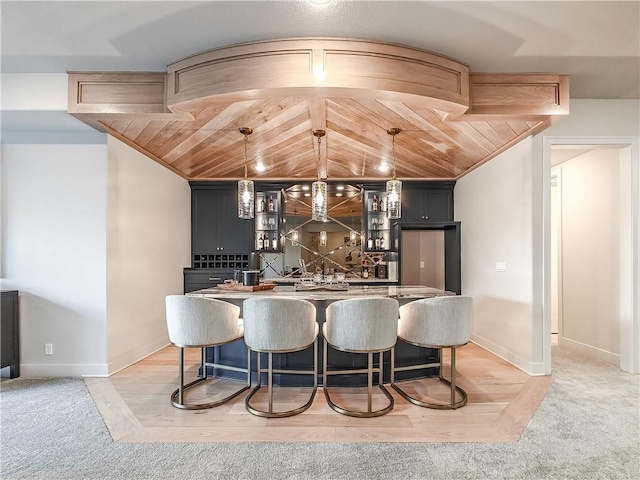 bar featuring hanging light fixtures, light colored carpet, baseboards, and indoor bar