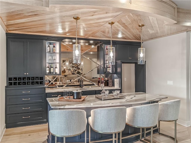 kitchen featuring a breakfast bar area, a center island with sink, wood ceiling, pendant lighting, and light wood-type flooring