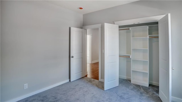 unfurnished bedroom with carpet, a closet, and baseboards