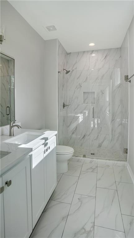 bathroom with marble look tile flooring, vanity, a marble finish shower, and recessed lighting