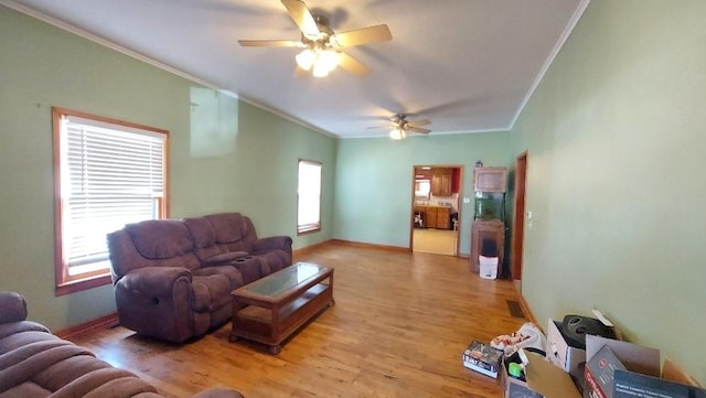 living area featuring crown molding, a ceiling fan, and a wealth of natural light