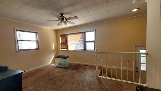 unfurnished room featuring baseboards, carpet floors, ceiling fan, and crown molding