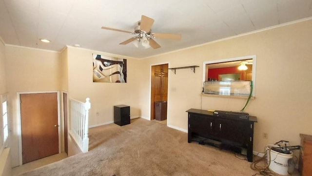 interior space featuring a ceiling fan, baseboards, carpet floors, and ornamental molding