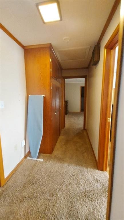 corridor featuring attic access, light colored carpet, and baseboards