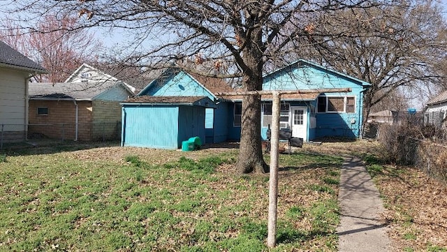 view of front of house with an outbuilding, a shed, a front yard, and fence