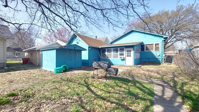 rear view of property with an outbuilding, a storage unit, fence, and a sunroom