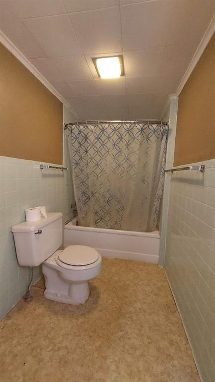 bathroom with crown molding, a wainscoted wall, toilet, tile walls, and shower / bathtub combination with curtain