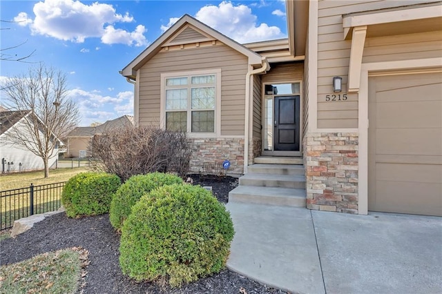 doorway to property featuring stone siding and fence