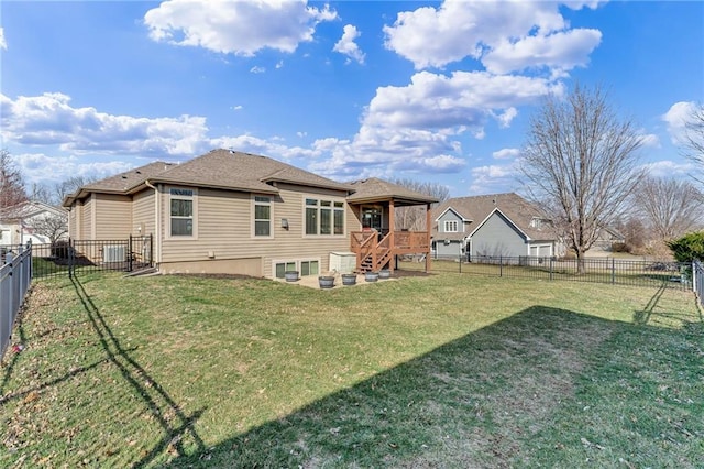 rear view of house featuring a lawn, a fenced backyard, and a shingled roof