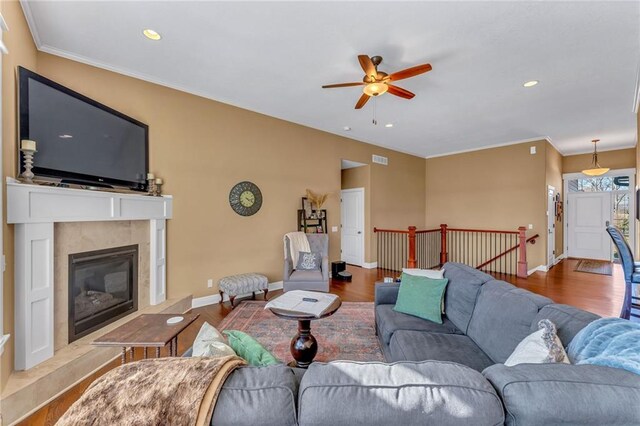 living room featuring a ceiling fan, wood finished floors, baseboards, and a fireplace