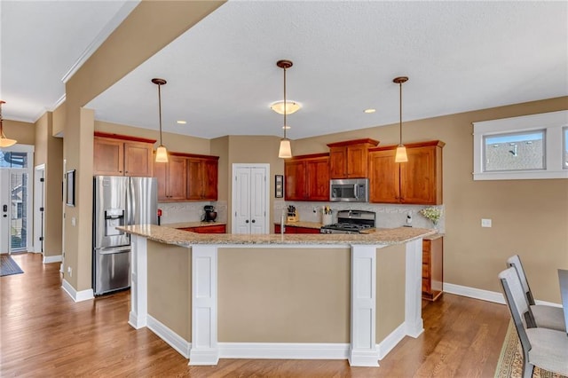 kitchen featuring decorative backsplash, stainless steel appliances, light wood-type flooring, and baseboards