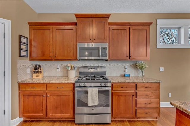 kitchen featuring light stone counters, brown cabinets, and appliances with stainless steel finishes