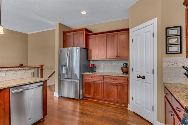 kitchen featuring tasteful backsplash, dark wood-style floors, brown cabinets, and appliances with stainless steel finishes