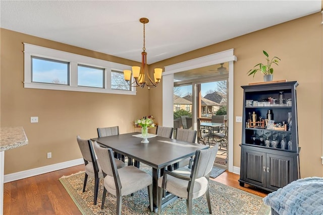 dining space with a notable chandelier, baseboards, and wood finished floors