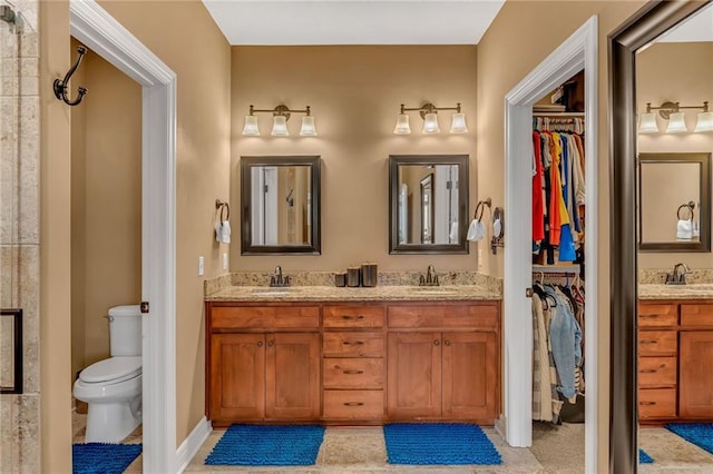 full bathroom featuring a walk in closet, double vanity, toilet, and a sink