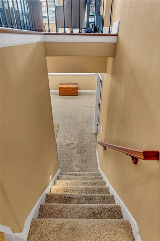 stairway with baseboards and carpet flooring