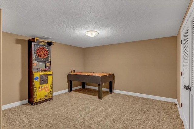 game room with light colored carpet, baseboards, and a textured ceiling