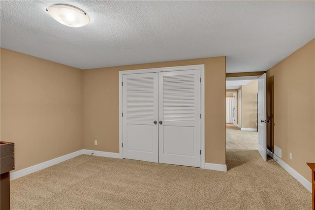 unfurnished bedroom featuring a closet, carpet flooring, a textured ceiling, and baseboards