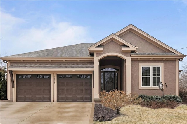 view of front of house with stucco siding, driveway, an attached garage, and a shingled roof