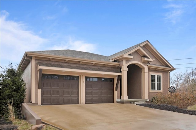 view of front of home with stucco siding, an attached garage, and driveway