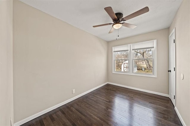 spare room with ceiling fan, dark wood-type flooring, and baseboards