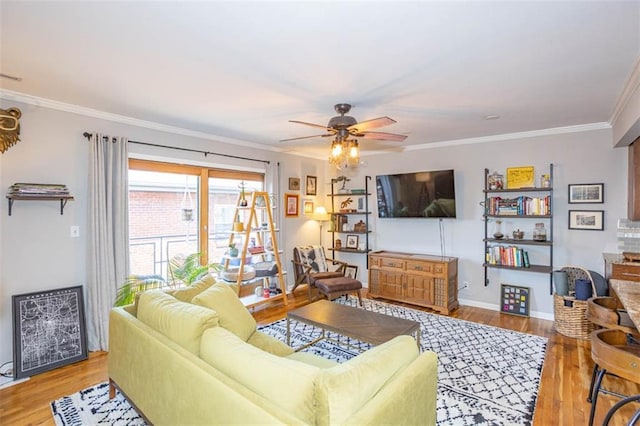 living area with baseboards, wood finished floors, a ceiling fan, and crown molding