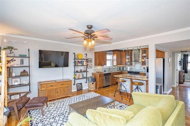 living area with baseboards, light wood-type flooring, a ceiling fan, and ornamental molding