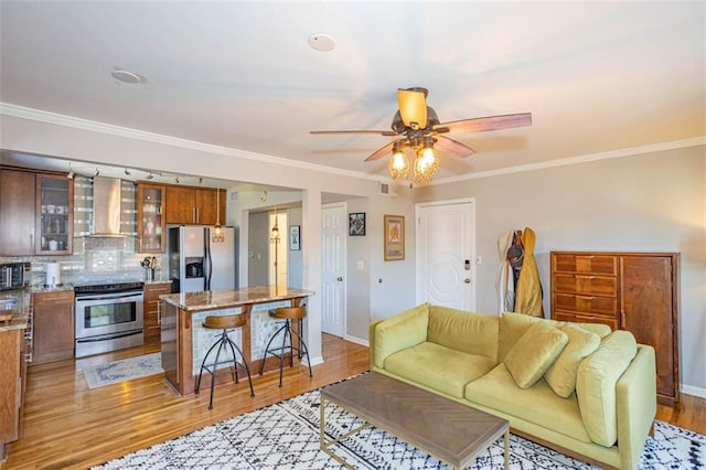 living room with crown molding, baseboards, light wood finished floors, and ceiling fan