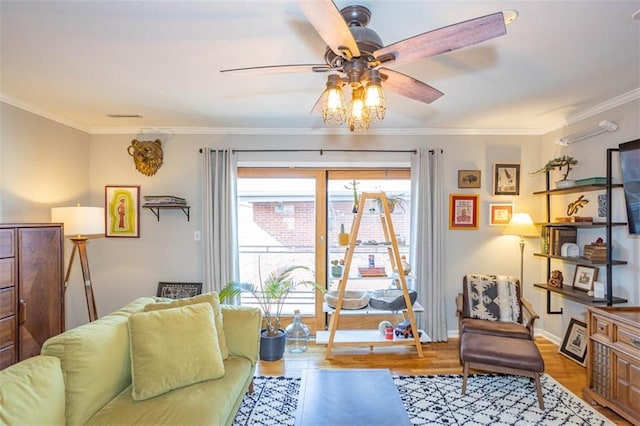 living area with crown molding, wood finished floors, a ceiling fan, and baseboards