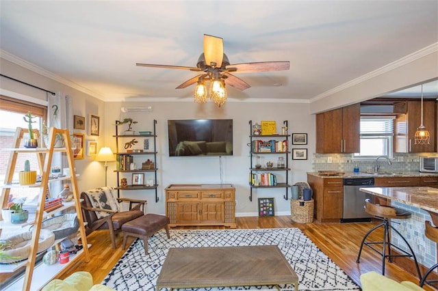 living area with light wood-style flooring, crown molding, and a ceiling fan