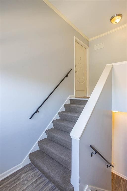 stairs with crown molding, wood finished floors, and baseboards