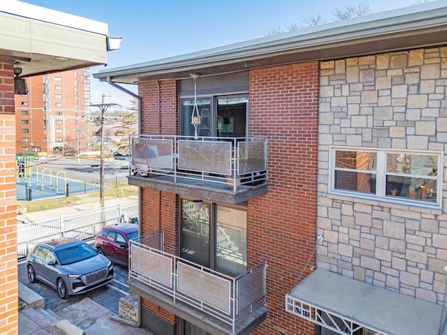 exterior space with a balcony, fence, and brick siding