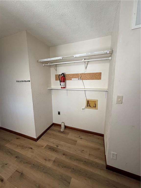 laundry area featuring laundry area, wood finished floors, baseboards, and hookup for an electric dryer