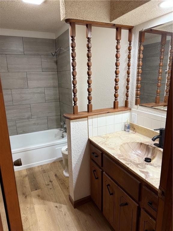 full bathroom featuring toilet, shower / tub combination, wood finished floors, a textured ceiling, and vanity