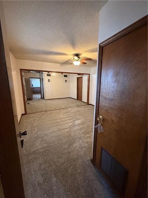 hallway with carpet and a textured ceiling