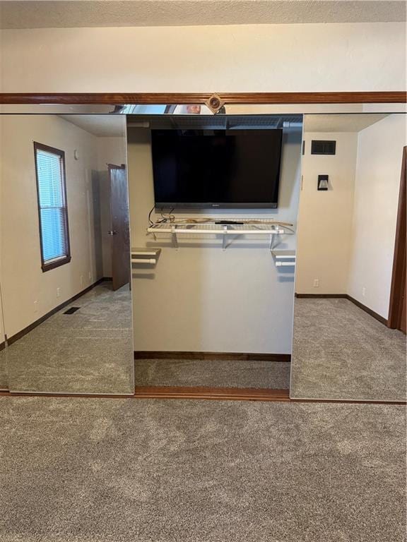 interior space featuring visible vents, a textured ceiling, baseboards, and carpet floors